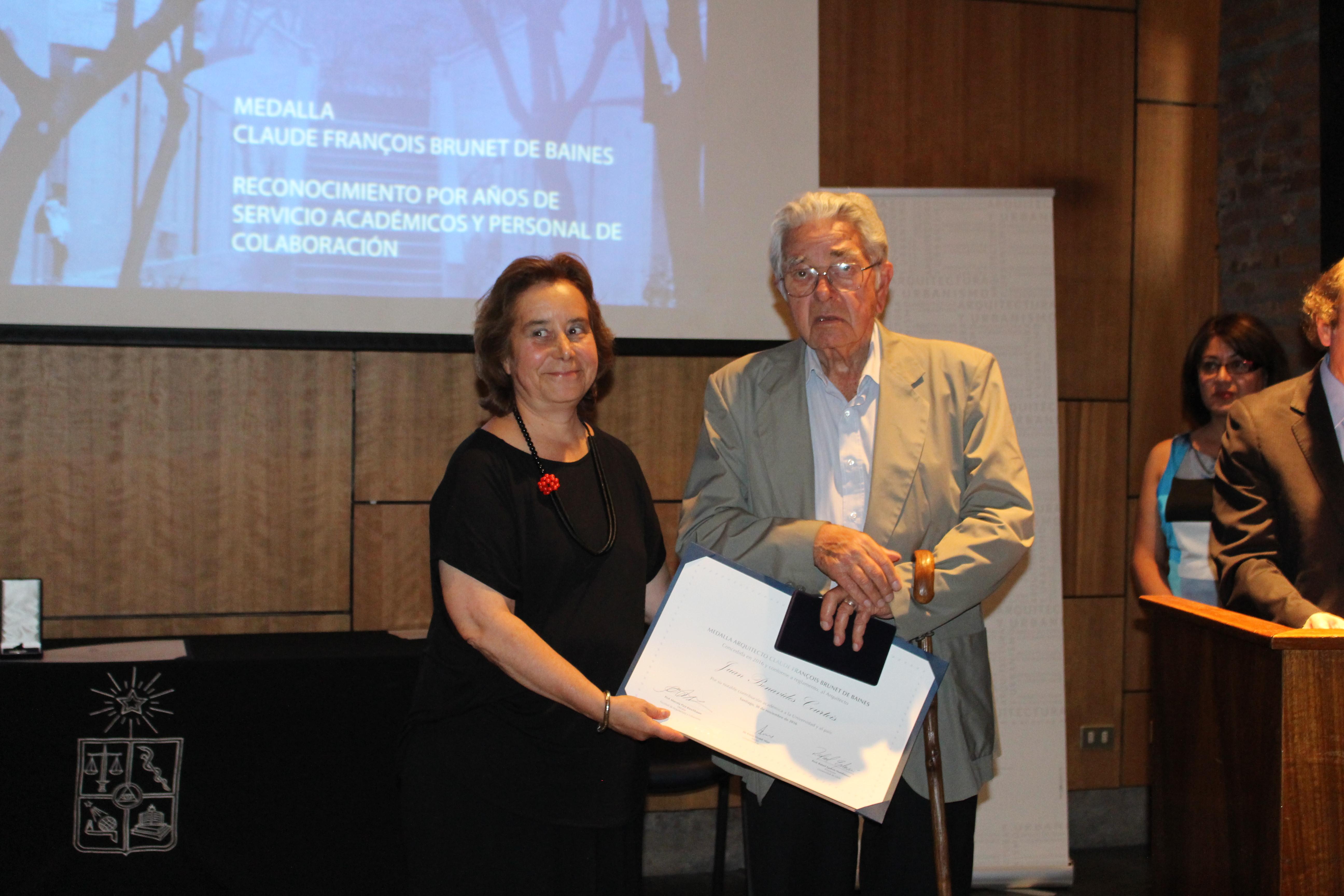 Decana Marcela Pizzi entregando medalla al arquitecto Juan Benavides.