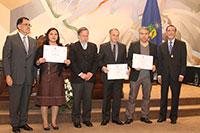 Los académicos premiados pertenecientes a la FAU: Joselyn Arriagada (en la fotografía su hermana, quién recibió); Manuel Amaya y Cristián Gómez, con las autoridades.